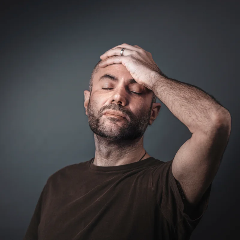 Man holding head, eyese closed, migraine suffering